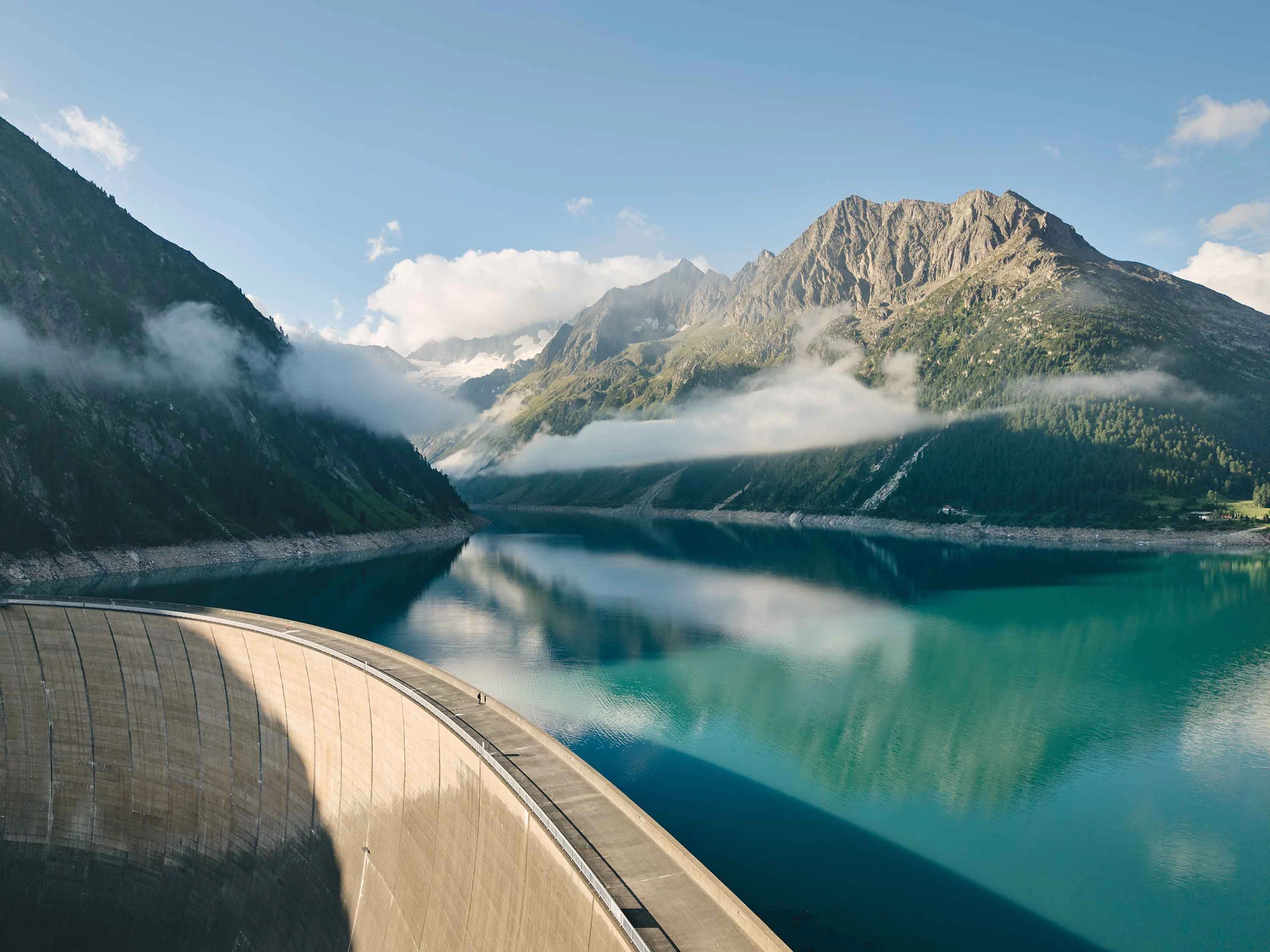 Ein Blick auf den Schlegeis Stausee. Im Vordergrund sehen wir die Staumauer. Im Mittelgrund den Stausee. Im Hintergrund sind die Berge.