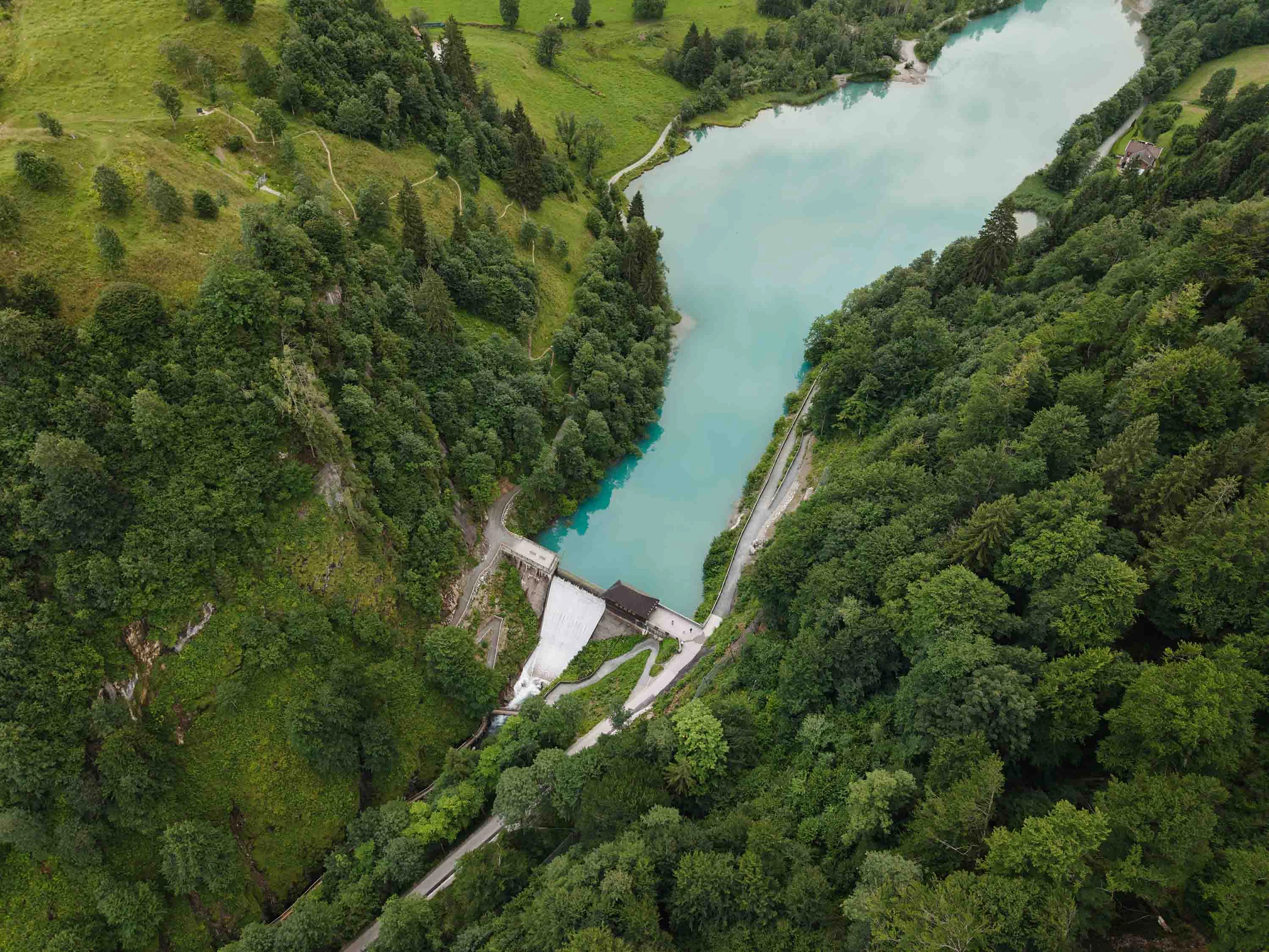 Ein Blick von oben auf die Sperre in Kaprun. Rechts und link befinden sich Wälder. Die Sperrmauer ist bildet den Abschluss des Stausees.