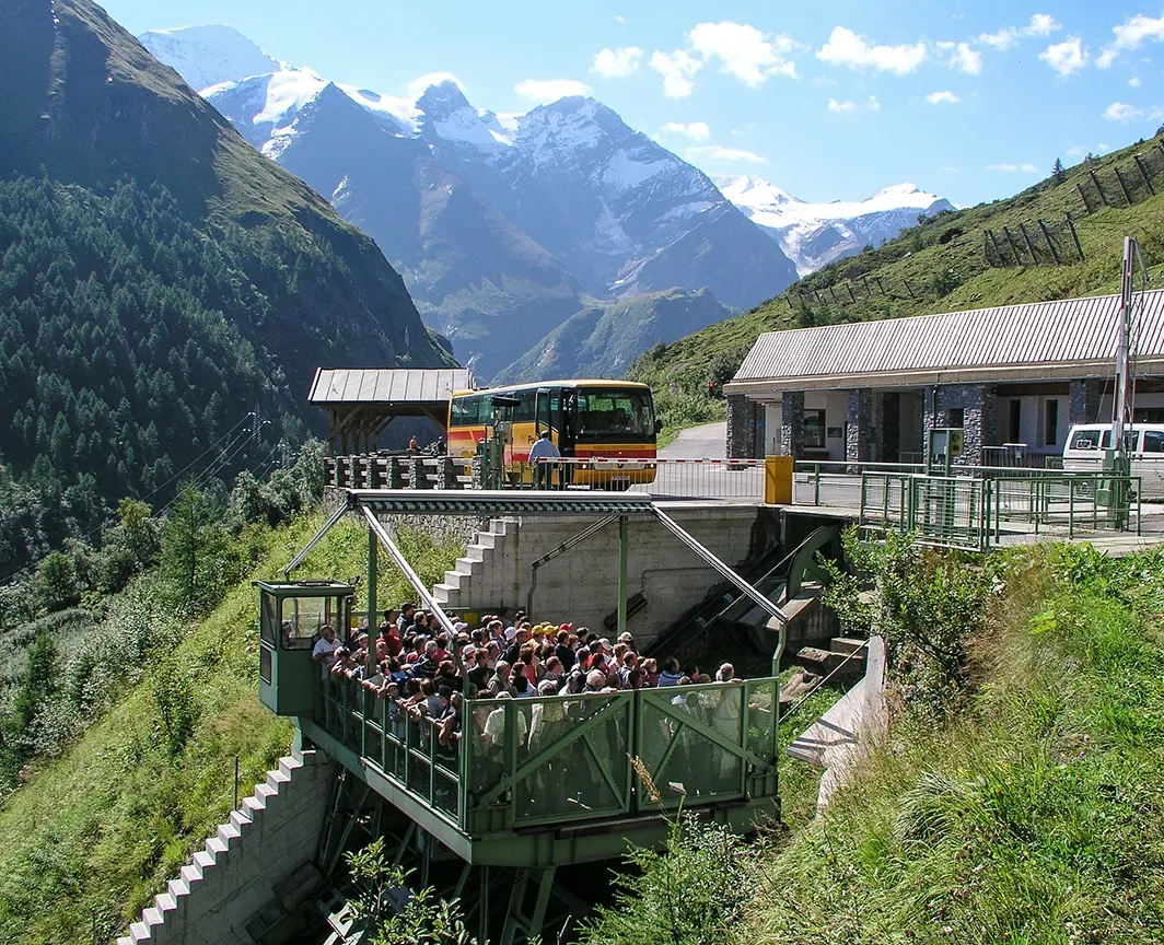 Wir sehen eine älter Farbaufnahme des Lärchwand Schrägaufzugs. In dieser Vorgängerversion besteht der Aufzug aus einer einfacheren offnen grünen Käfigkonstruktion. Zahlreiche Menschen fahren mit dem Aufzug gerade wieder nach unten.