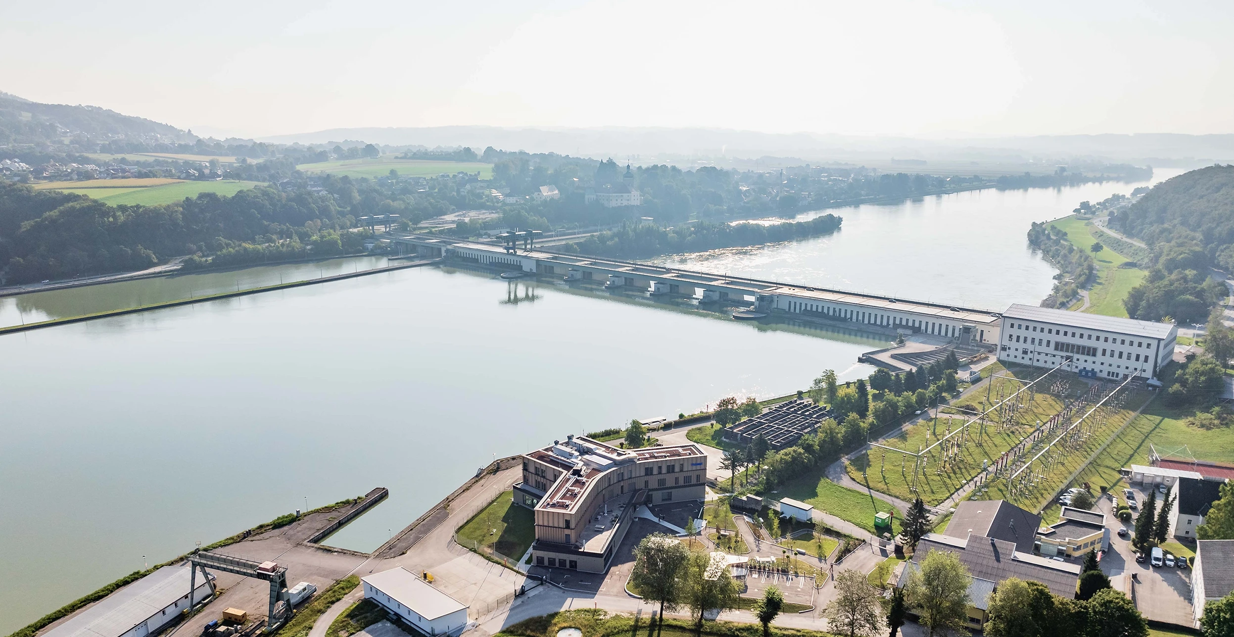 We look down on the Ybbs-Persenbeug power station with its apprentice centre. The sun is shining and the meadows are green.