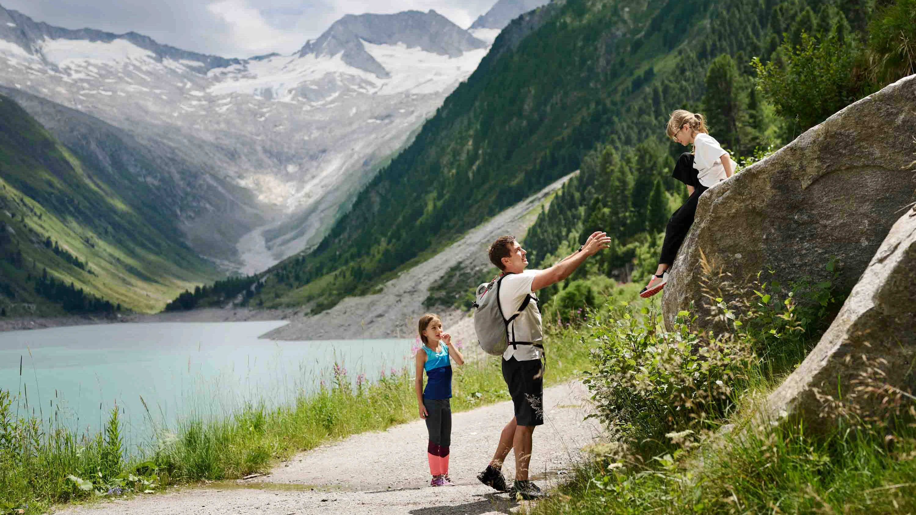 A father with two daughters is out and about at Schlegeis Reservoir. On the left we can see the reservoir, with the mountains in the background.