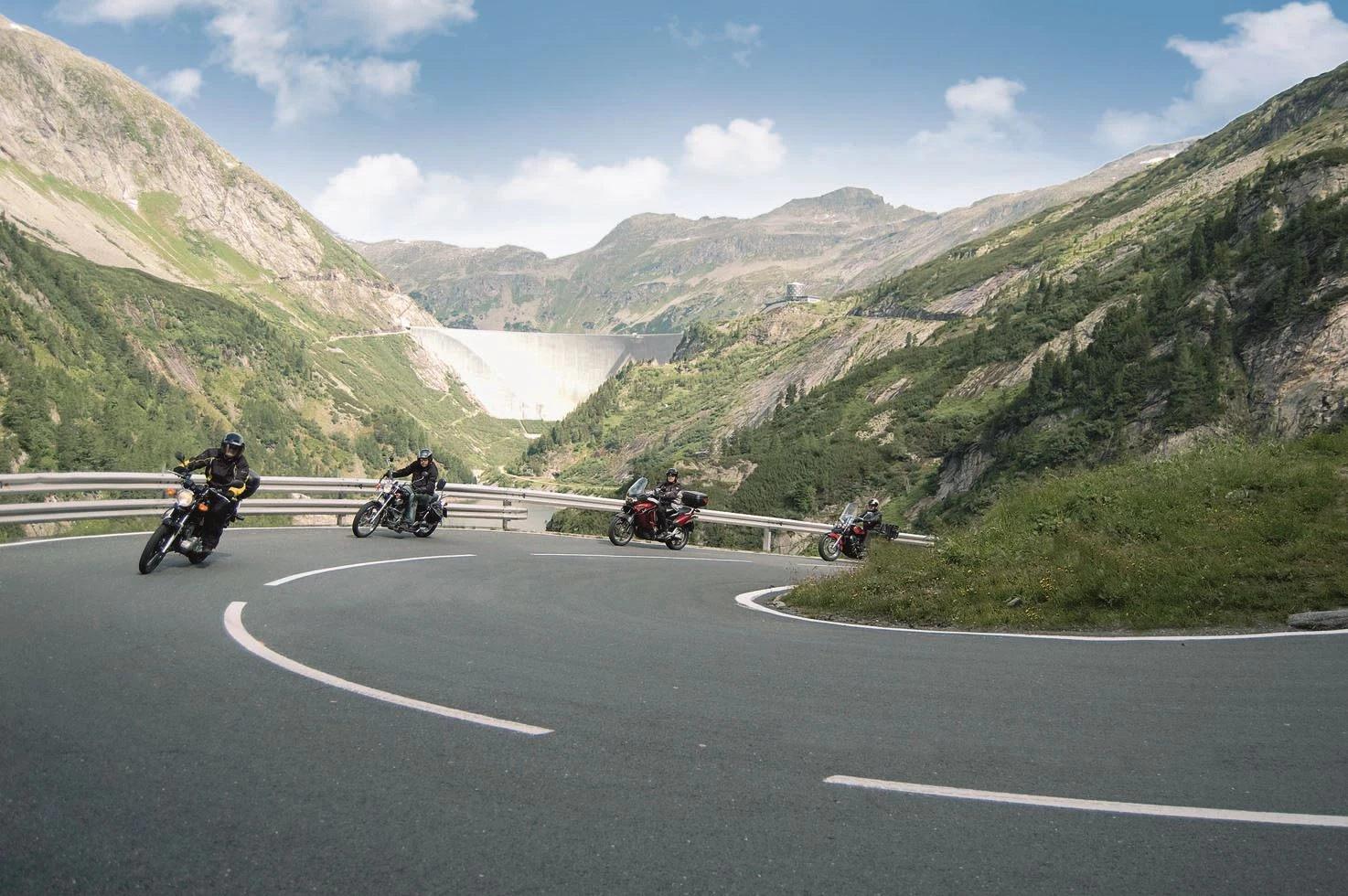 Wir sehen 4 Motorradfahrer auf der Zufahrtsstraße der Kölnbreinsperre. im Hintergrund sehen wir die Staumauer. Das Winter ist prächtig.